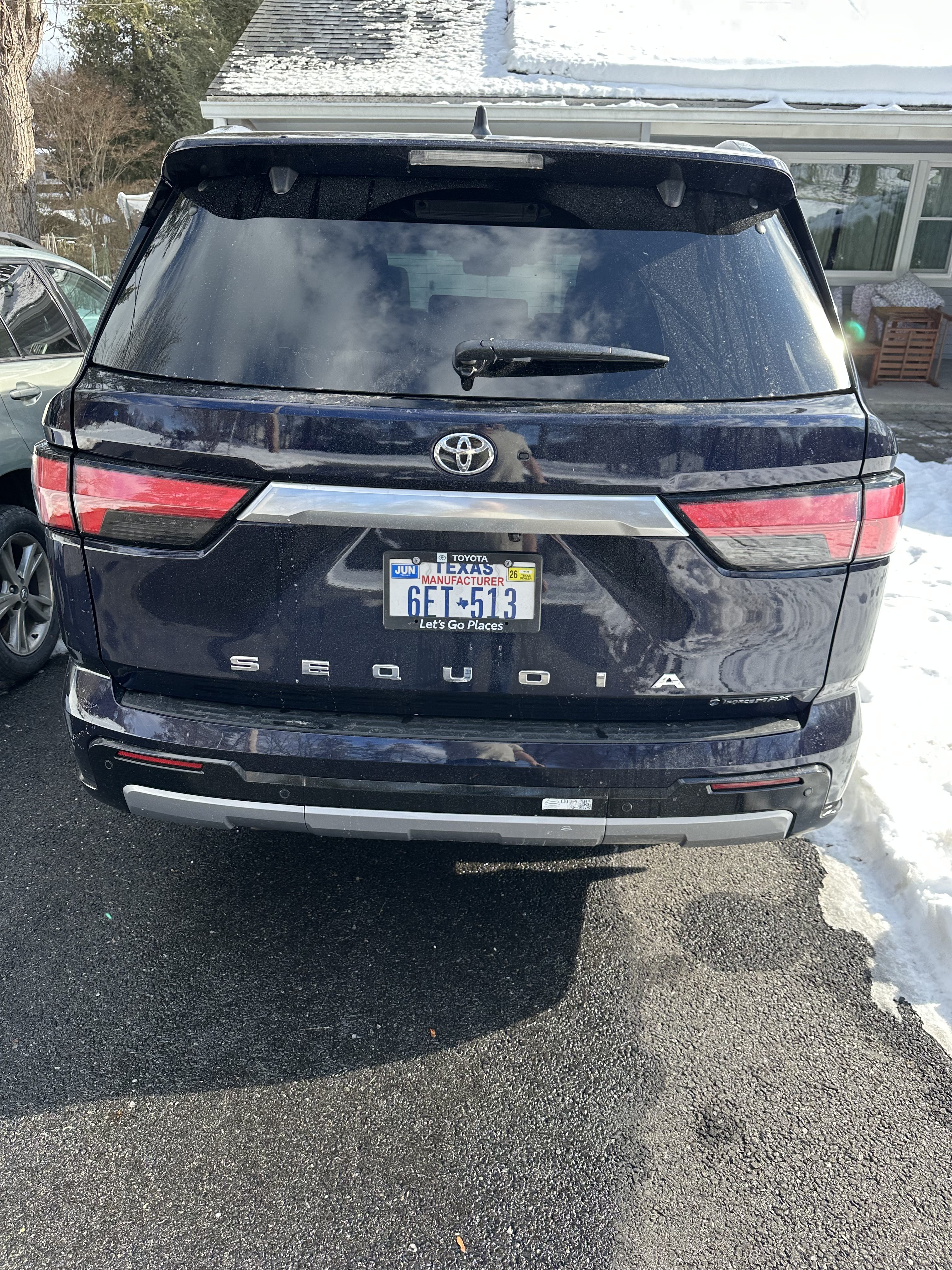 Vue arrière d’un Toyota Sequoia noir garé sur une allée enneigée.