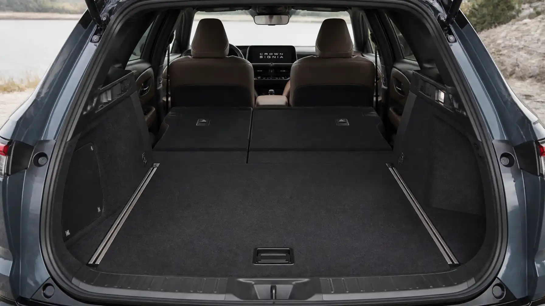 Coffre vide d'un SUV avec sièges arrière rabattus, montrant un espace de chargement agrandi et des sièges avant avec un écran central indiquant « CROWN SIGNIA »